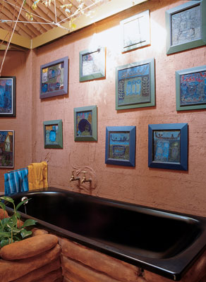 
The tub is bathed in light from the skylight, and the surrounding mud walls show off Gernot’s oil paintings.

